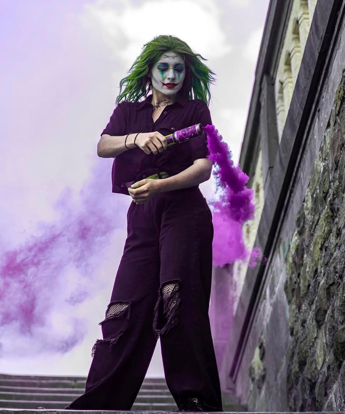 The same Joker character on stone steps, holding a purple smoke flare.
